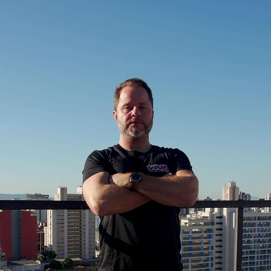 Felipe, da VIVA, de braços cruzados numa cobertura, com a cidade de São Paulo ao fundo
